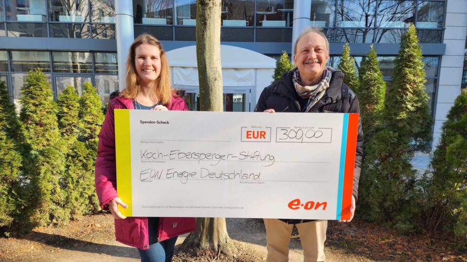 Sophia Richter und Dr. Ralf Ebersperger lächeln in die Kamera und halten einen Spendenscheck der e.on Energie Deutschland in den Händen.